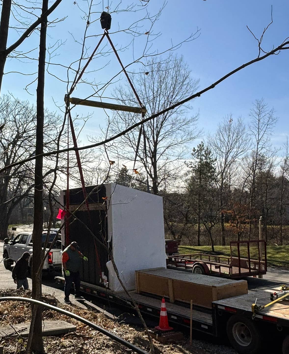 Prefabricated gatehouse on a flatbed trailer before installation, surrounded by trees and construction equipment.