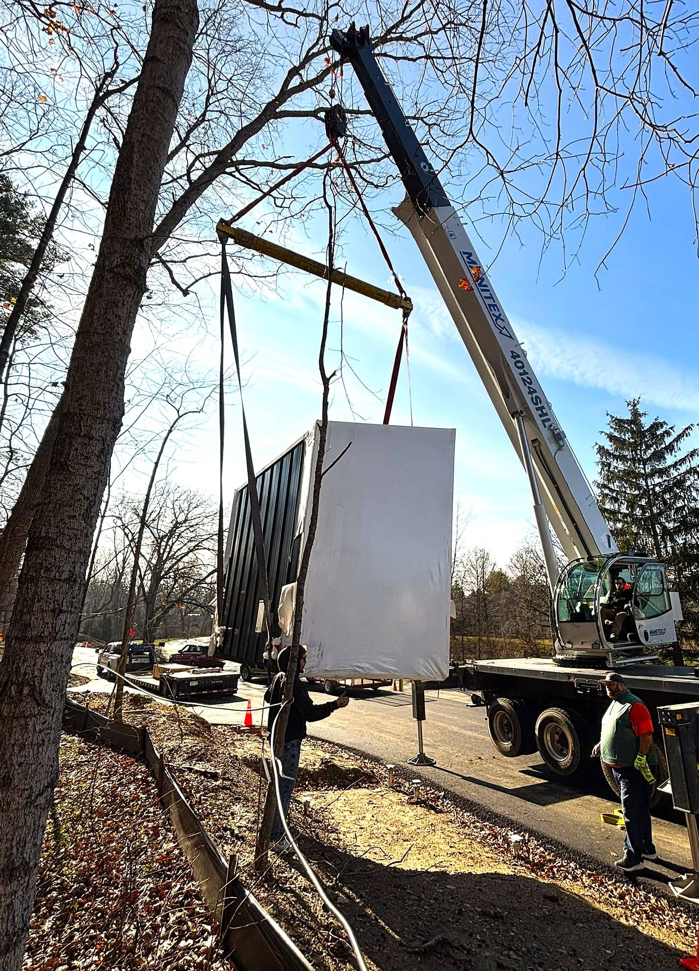 Workers guide the prefabricated gatehouse into place as it is lifted by a crane.